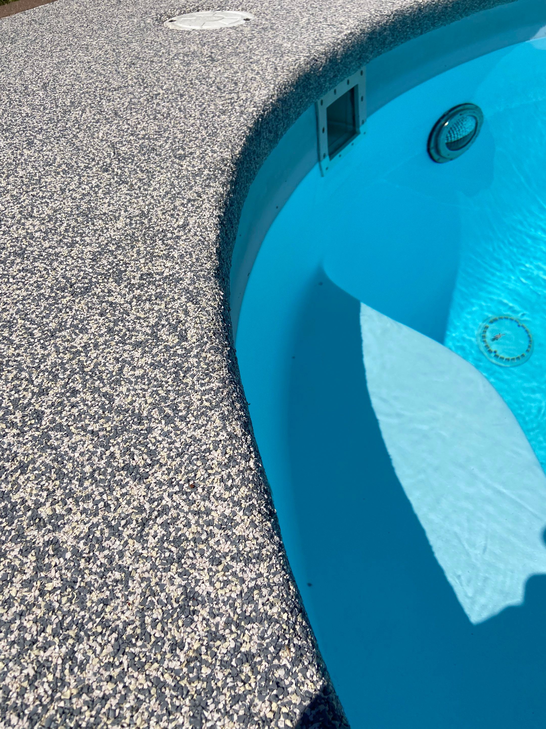 Resurfaced Fox pool deck beside clear blue water